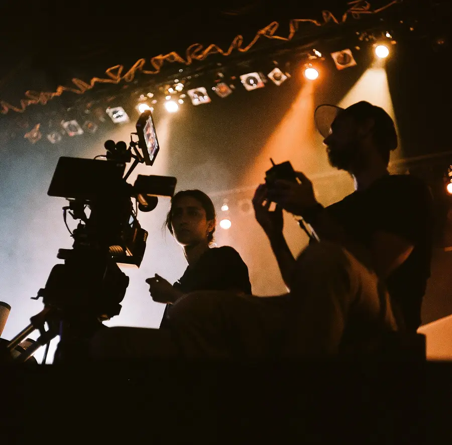 Camera and crew silhouettes under stage lights